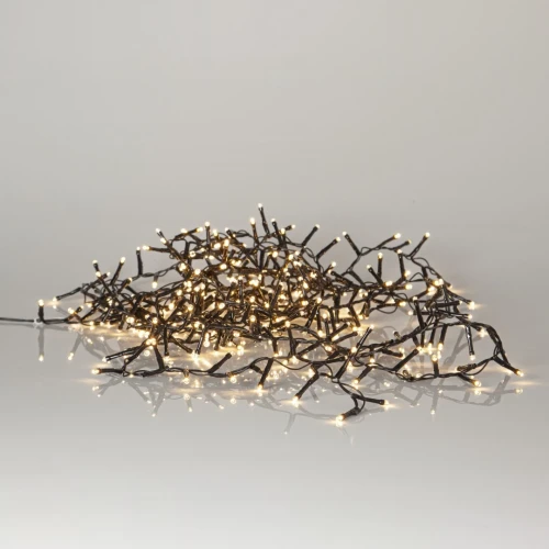 Zwinięty łańcuch świetlny z ciepłymi diodami LED na czarnym przewodzie, odbijający się od jasnej, lśniącej powierzchni.