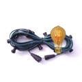 Zielony przewód girlandy ogrodowej z czarnymi oprawkami E27 i żarówką LED TA60 2,5W 2000K z bursztynowego szkła z serii Decoled Amber, emitującą ciepłe światło o dekoracyjnym, spiralnym żarniku.