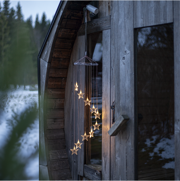 Świetlna girlanda LED z drobnymi gwiazdkami miękko oświetla drewnianą elewację, dodając zimowemu otoczeniu ciepła i spokojnego, nastrojowego klimatu.