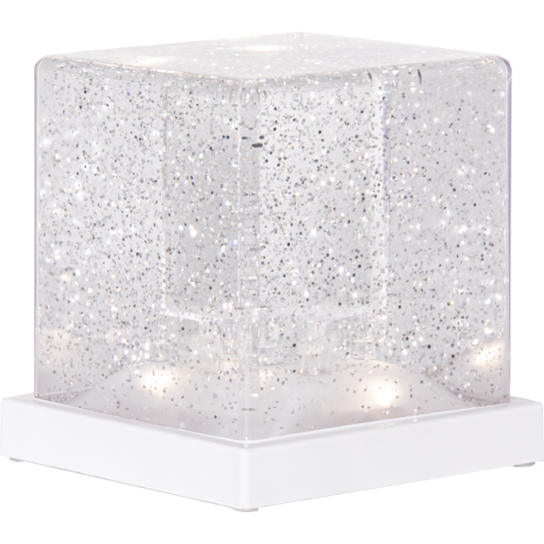 Dekoracja świetlna w formie przezroczystego sześcianu z brokatowym wnętrzem na białej podstawie prezentowana na jasnym tle.