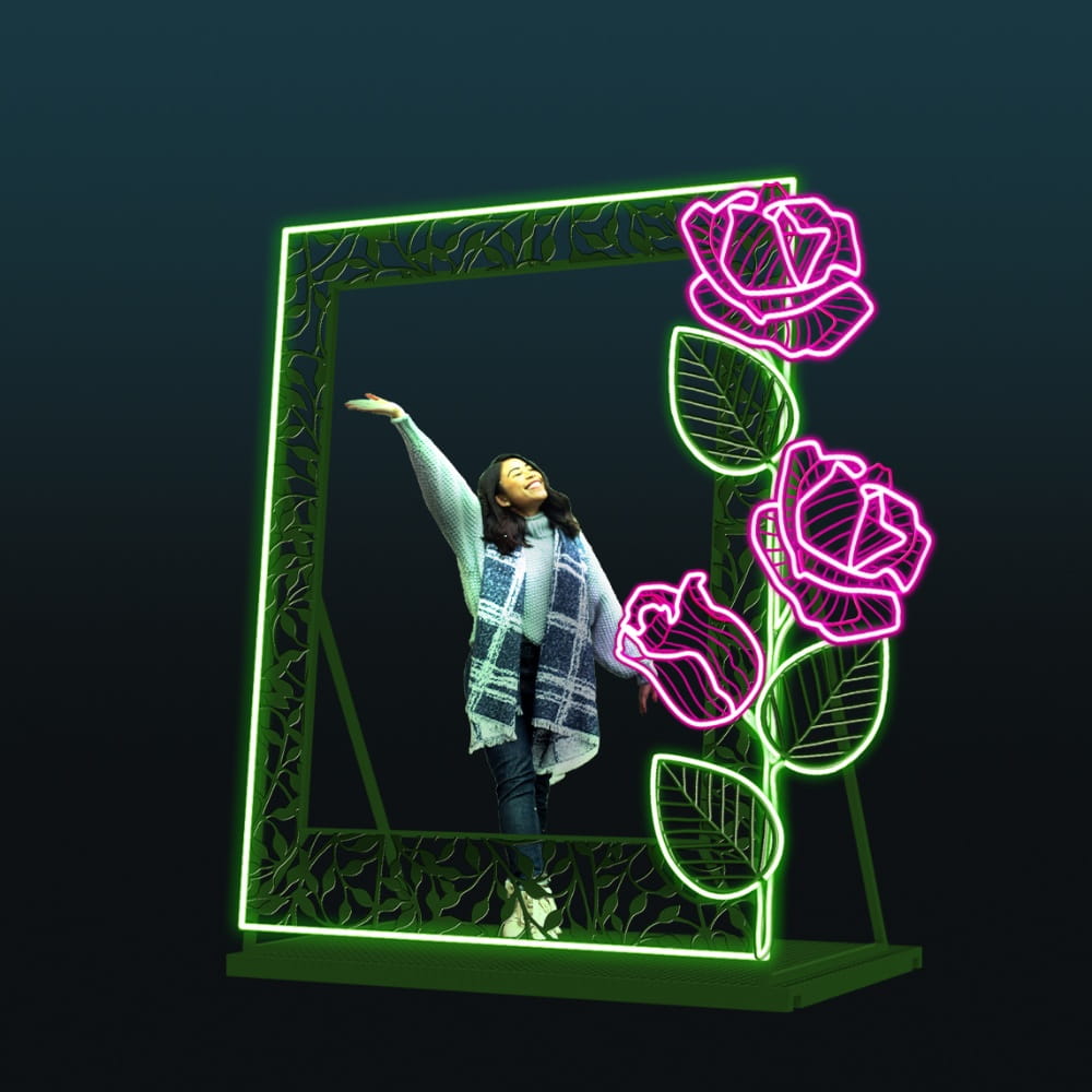 Dekoracyjna ramka LED z motywem kwiatów na ciemnym tle, fotopunkt z neonowymi różowymi kwiatami i zieloną konstrukcją, nowoczesna instalacja świetlna do eventów, galerii handlowych i przestrzeni miejskich przyciągająca uwagę.