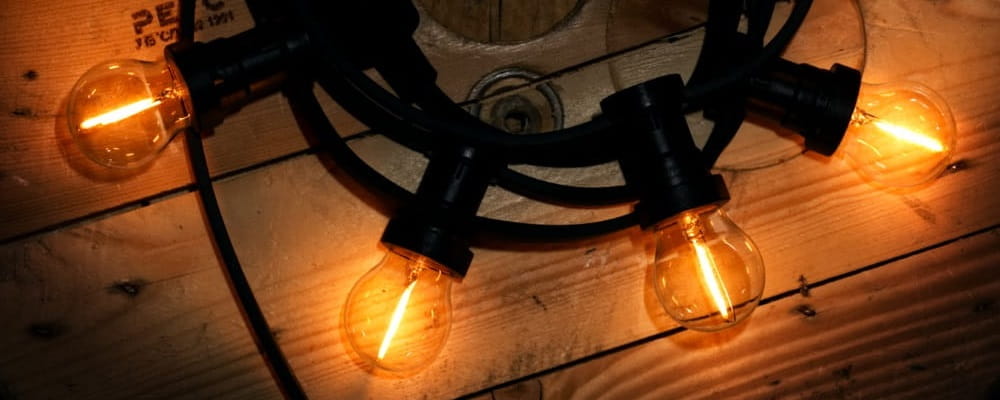 Girlanda MIMOSA z kilkoma żarówkami LED G45 emitującymi ciepłe światło, tworząca nastrojową atmosferę w wieczornej aranżacji.