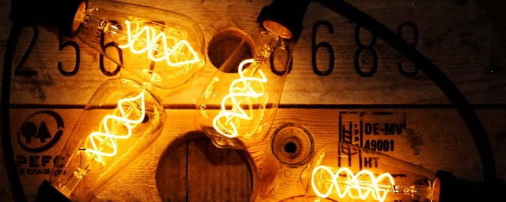 Girlanda ogrodowa z żarówkami LED ST64 4W 2100K z 3-stopniowym ściemnianiem, ułożona na drewnianej szpuli z cyframi. Żarówki emitują intensywne, ciepłe światło, a widoczne spiralne żarniki nadają im efekt retro.