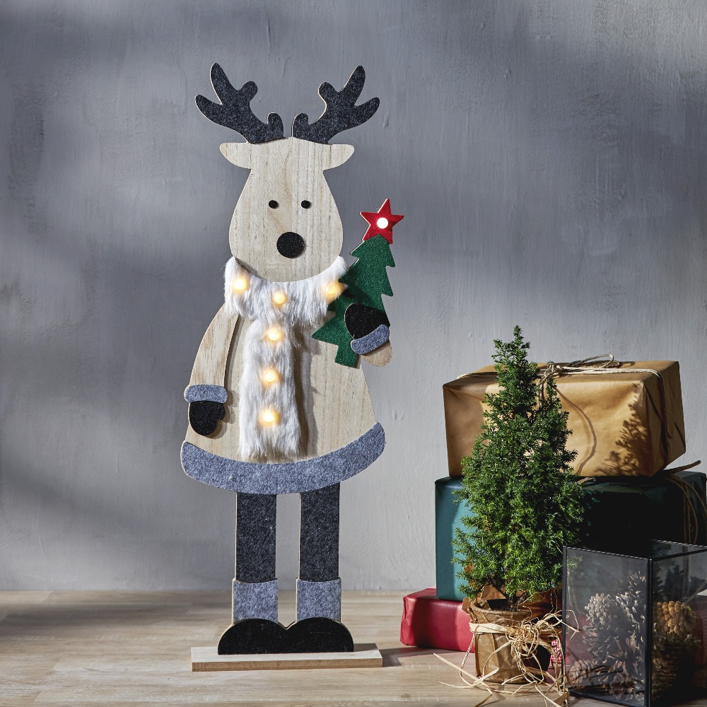 Drewniany renifer LED z podświetlanym futrzanym szalikiem i choinką z czerwoną świecącą gwiazdą, stojący obok małej choinki i prezentów, rozświetla ciepłym światłem przytulny świąteczny kącik.