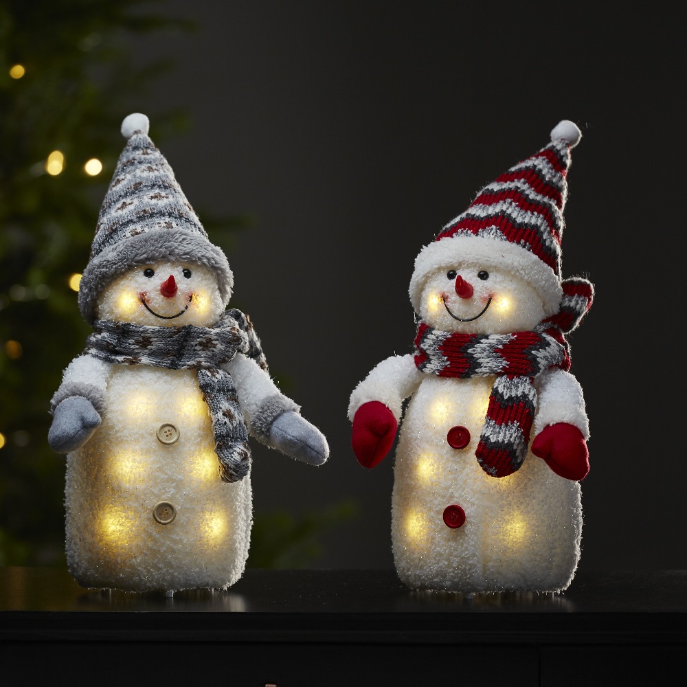 Dwie świąteczne figurki LED bałwanki w szaro-czerwonych czapkach i szalikach, z podświetlanym wnętrzem, ustawione obok siebie na blacie.