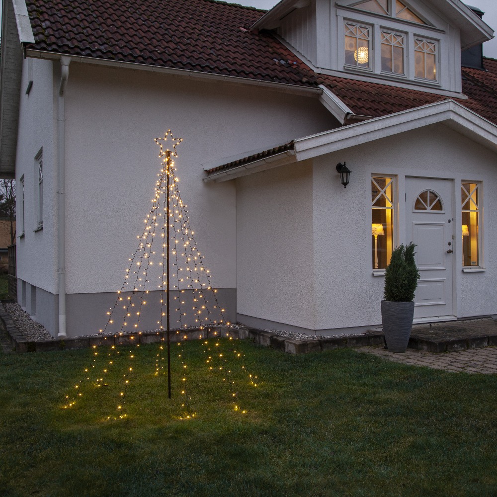 Świąteczna dekoracja LED w kształcie choinki z gwiazdą, ustawiona przed domem. Ciepłe światło tworzy subtelny klimat i podkreśla przestrzeń ogrodu oraz elewację budynku.