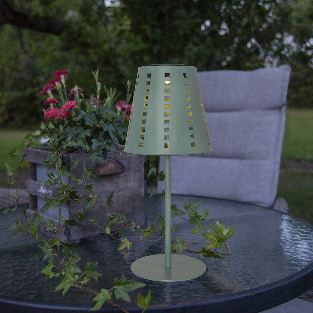 Solarna lampa stołowa ogrodowa LED zielona, oświetlenie tarasu na stoliku wśród roślin.