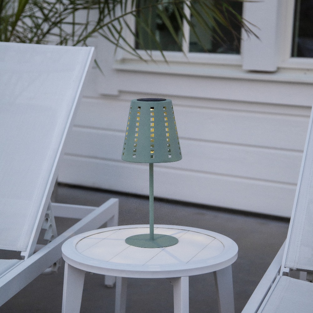 Solarna lampa stołowa ogrodowa LED zielona na stoliku kawowym przy leżakach, oświetlenie tarasu.
