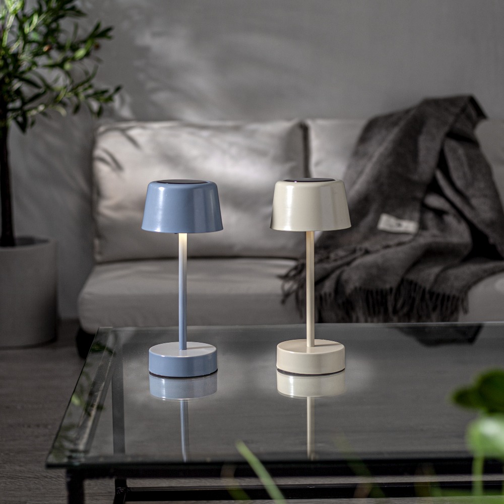 Dwie lampy stołowe LED zasilane solarnie i przez USB, ustawione na stoliku w domowej aranżacji.