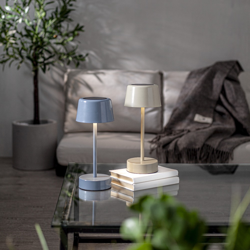 Niebieska i beżowa lampa stołowa LED solarna z możliwością ładowania przez USB, ustawione na stoliku w eleganckim wnętrzu