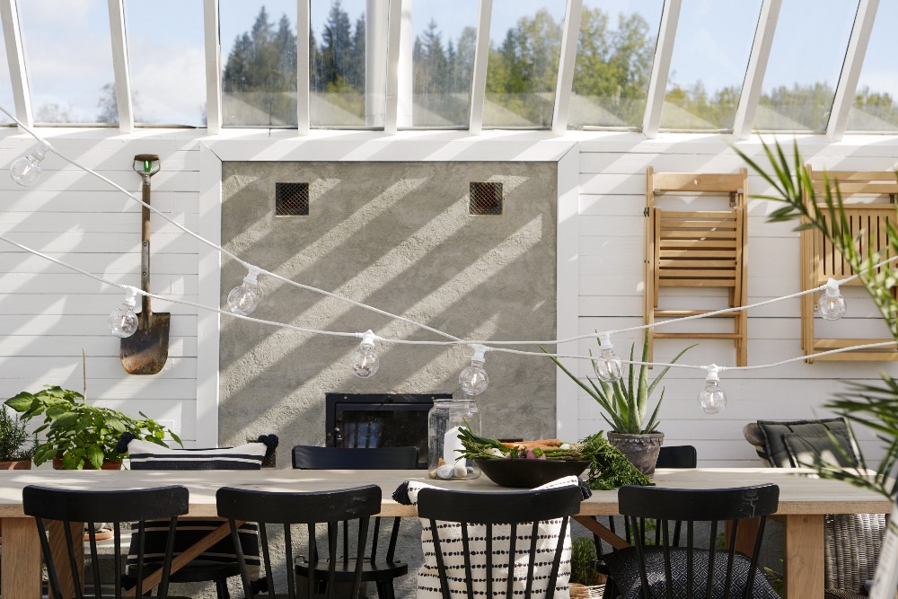 Girlanda świetlna z żarówkami LED G95 1W filament o ciepłej barwie 2700K zawieszona nad stołem na tarasie. Biały przewód i plastikowe klosze zapewniają trwałość, idealne oświetlenie do ogrodu, restauracji i przestrzeni zewnętrznych.