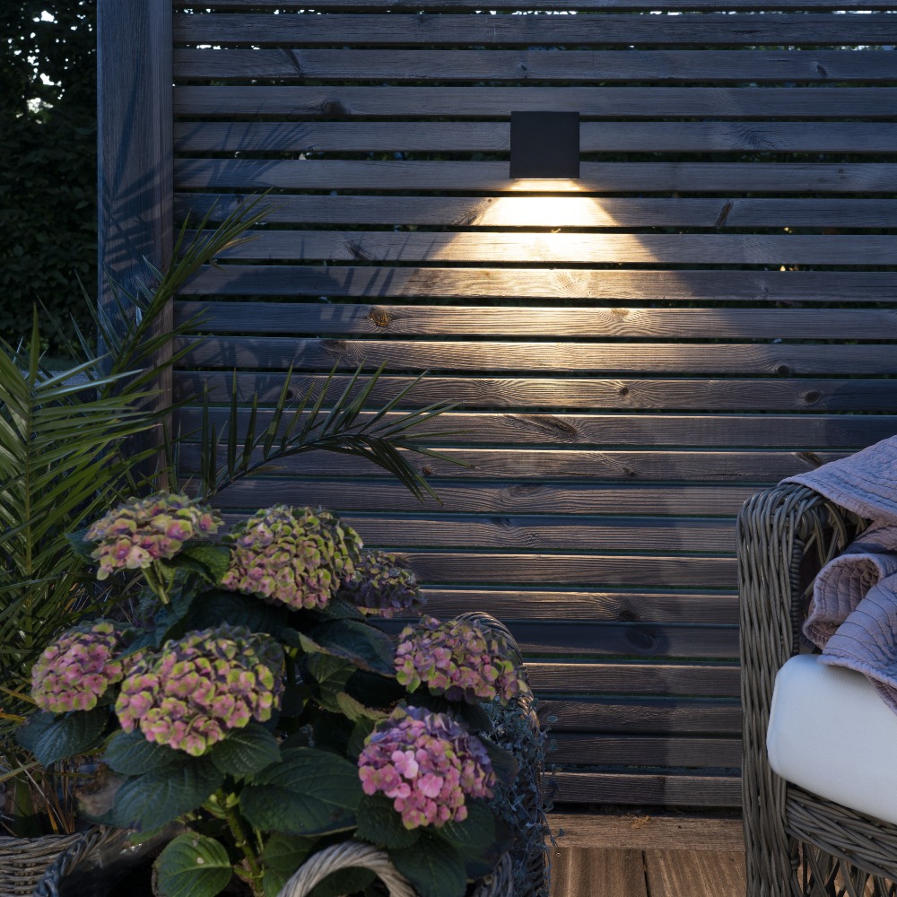 Solarny kinkiet zewnętrzny doświetla taras i ogród, podkreślając aranżację roślin oraz elementów ogrodzenia.