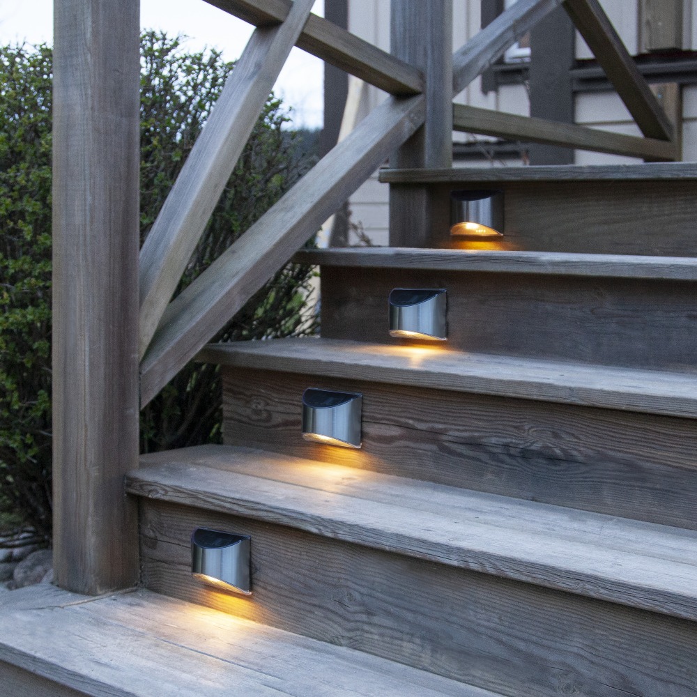 Lampy solarne zamontowane na drewnianych stopniach, delikatnie oświetlające kolejne poziomy i ułatwiające poruszanie się po zmroku.