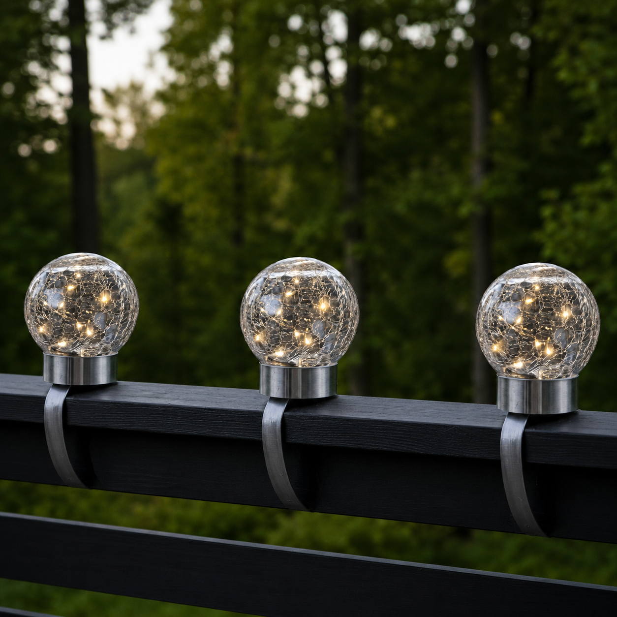 Trzy solarne lampy LED w formie szklanych kul z efektem spękanego szkła zamontowane na poręczy balkonu, nowoczesne oświetlenie dekoracyjne na taras i do ogrodu z ciepłym światłem.