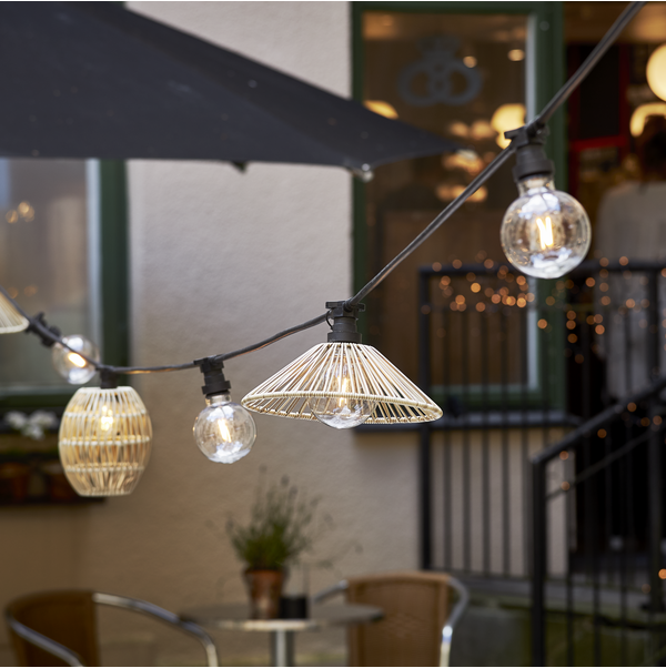 Girlanda CONNECTA zamontowana przy elewacji lokalu, z oprawkami E27 i dekoracyjnymi kloszami nad stolikami kawiarnianymi.